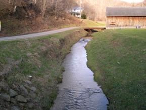 Figure 177. McKnown Creek, Appalachian Plateau-looking downstream at bridge. Photo. This is looking downstream at the bridge. The cross section is trapezoidal, and the channel is well-aligned with the bridge. 