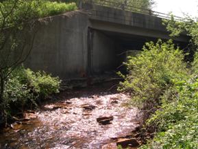 Figure 192. Reids Run, Appalachian Plateau-looking upstream at bridge. Photo. This is looking upstream at the bridge, again showing that lateral movement has caused the thalweg to press against the left abutment.