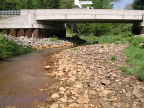 Figure 195. Piney Creek, Appalachian Plateau-looking downstream at bridge. Photo. This is looking downstream at the bridge and the large bar devoid of vegetation. The channel thalweg is hugging the left abutment. 