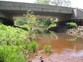 Figure 196. Piney Creek, Appalachian Plateau-looking upstream at bridge. Photo. This is looking upstream at the bridge, showing some misalignment of the channel in the bridge opening. The left bank is protected with riprap.