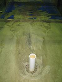 Figure 57. Photo. Result of a pier scour test with a graded sediment. This photo shows a scour hole around a pier with larger material collecting at the bottom of the hole.
