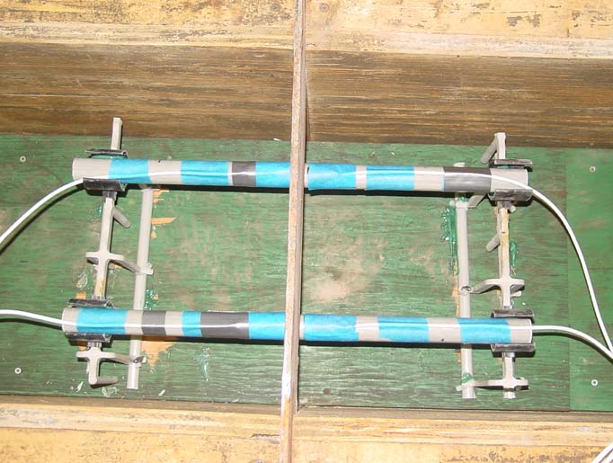 This photo shows inside walls of wood formworks that have been oiled for easy demolding of the concrete pavement slabs. It also shows dowel bars instrumented with strain gauges, which are supported on dowel baskets and centered equally on both sides of the steel plate. A steel plate with the dimensions of the slab joint is placed in the middle of the slab to be lifted off after concrete curing to simulate a contraction or sawcut joint in the concrete pavement. 