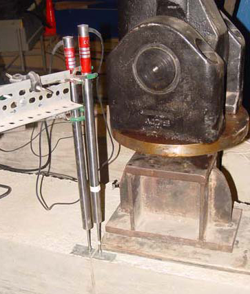 This photo shows a close-up view of a slab at the joint location where two linear variable differential transformers (LVDTs) are used to measure slab deflections at loaded and unloaded sides of the joint as the load is applied from the hydraulic actuator system through a steel plate.