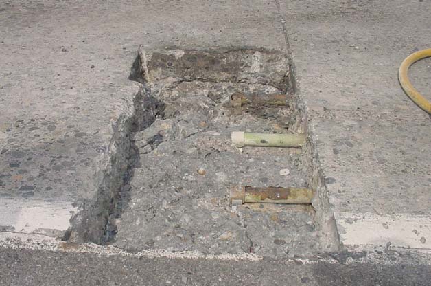 Figure 1. Photo. Exposed failures with rusted dowel bars (Washington State Department of Transportation Pavement Guide). This photo shows a portion of the jointed concrete pavement which is excavated to show two rusted, corroded steel dowel bars approximately at the mid-height of the slab cross section and spaced apart by 30.48 cm (12 inches).