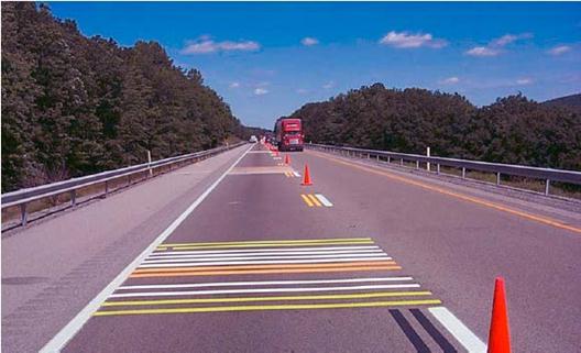 This photo shows a two-lane National Transportation Product Evaluation Program (NTPEP) test deck with taped transverse pavement markings in the right travel lane.