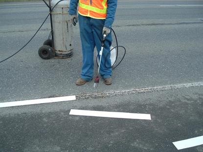 This photo shows a worker applying preformed thermoplastic on a roadway.