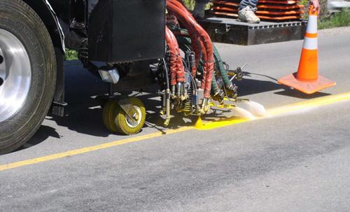 This photo shows a double bead drop using flare nozzle guns on a liquid material on a roadway.