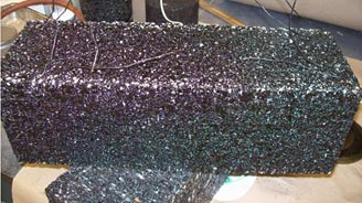 This photo shows a close-up view of the compacted slab with embedded transducers. It is a black rectangular block with wires sticking randomly out of it.