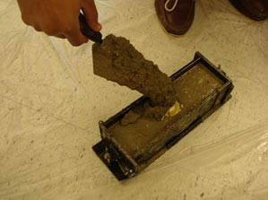 This photo shows a piezo-transducer embedded in concrete. The transducer is placed in a mold and is covered in wet concrete.