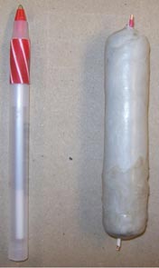 This photo shows a white protective layer lying next to a pen. The protective layer is about double the width of the pen and slightly shorter.