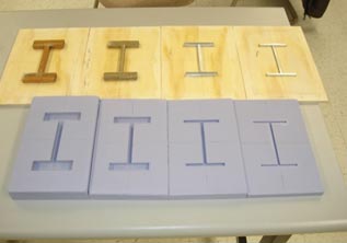 This photo shows four different H-shaped molds all laid out, ranging in size and thickness. The matching molds are laid out above the H-shaped wood or metal