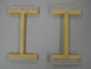 This photo shows two I-shaped objects sitting next to each other. They are both yellow and have a strip of grey running across the top