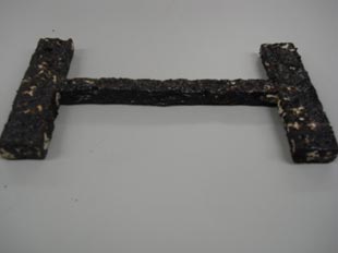This photo shows the recovered specimen after the compaction test has been preformed. The prototype is covered almost entirely with black asphalt.