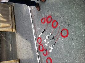 This photo shows the eight sensors laid out on the cement. They are attached to red wires that are coiled up next to them.