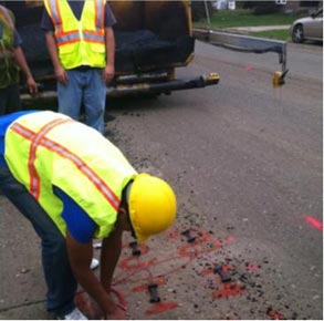 This photo shows a worker placing sensors on markings on the roadway.