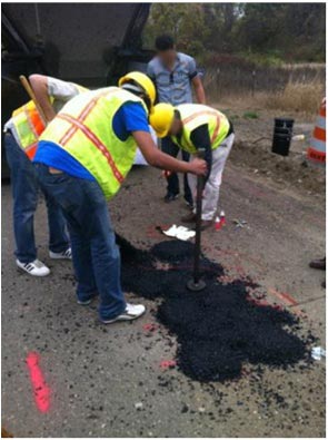 This photo shows the workers covering the last sensor of hot mix asphalt (HMA) patches.