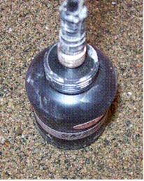 This photo shows a top view of the Dynamax sensor model (SM)200 moisture gauge. It is a black cylindrical object and is sticking into the sand. There is a cord coming out of the top.