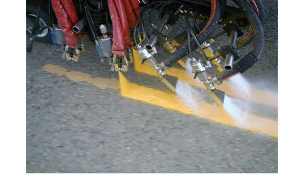 Close-up of glass bead application to long lines. The image shows a close-up an automatic bead drop delivery system placing beads onto marking material.