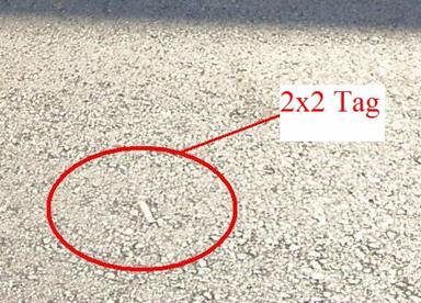 This photo indicates where a radio frequency identification (RFID) tag has surfaced, which is represented by a larger void and discoloration in the pavement. The size of this void is roughly the size of the encapsulated RFID tag explained in the previous photos. The surfaced tag is circles and labeled 2x2 Tag.