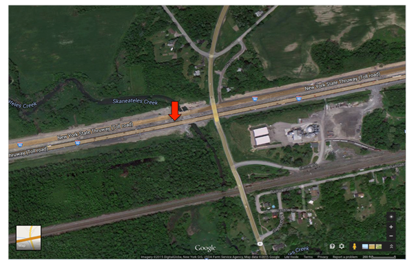 This photo is an aerial image showing a map of the location where the radio frequency identification (RFID) tags were embedded. Two highways are shown on the map. The main highway, where the RFID tags are embedded is Interstate 90, also labeled Governor Thomas E. Dewey Thruway and New York State Thruway, and runs roughly east to west. In the middle of the image, NY highway 31, also labeled N Main St, runs roughly north to south and intersects Interstate 90. Just west of the intersection, an arrow indicates where the RFID tags are embedded. Most of the land around the highways is covered in grass or trees.