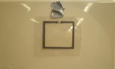This photo shows a loop antenna that is represented by a square. The antenna is 0.2 inches wide and has a total length of 12.9 inches. At the top center of the loop is the radio frequency identification chip. The loop is painted with conductive carbon paint on a flexible plastic substrate.