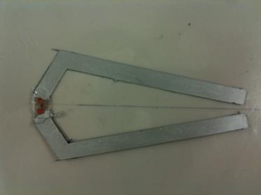This photo shows the C-shaped silver dipole antenna that is made of silver conductive paint. At the center of the C is the radio frequency identification (RFID) chip and antenna. From this, a rectangle extends at an angle of approximately 45 degrees upward. A longer rectangle connects to this and extends downward back toward the centerline of the C. A symmetrical piece extends downward from the RFID chip and antenna that represents the bottom part of the C. Together, the antenna looks like a C where the top and bottom of the C almost connect at the centerline.