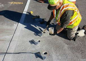 Figure 28. Photo. Partial grouting of the sensors. This photo shows a worker partially grouting the sensors in the core holes.