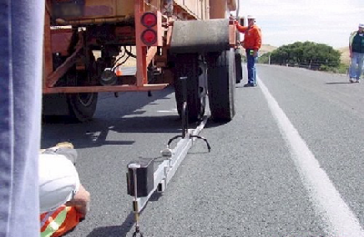 This photo shows a Benkelman beam placed between dual tires of a single axle loaded to 80 kN (18,000 lbf).