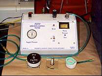 Figure 2. Photo. The Pneumatic Adhesion Tensile Testing Instrument (PATTI) is shown. The PATTI device includes test equipment such as piston, thread plate, air supply hoses, rubber gasket, loading fixture, asphalt sample, and glass substrate.