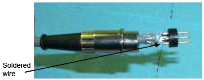 Photograph shows an internal view of the DIN plug. An arrow indicates the location of the soldered wire.