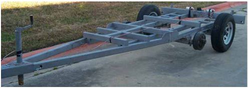 Photograph shows a trailer that has been stripped and sandblasted and is ready to go to a powder coat facility. The trailer has been stripped of all paint and parts as part of the major overhaul. Highlighted are some cracks, corrosion, and missing bolts that were repaired, replaced, or cleaned during the overhaul.