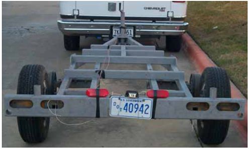 Photograph shows the rear view of a trailer. The trailer has been stripped of all paint and parts as part of the major overhaul. Highlighted are some cracks, corrosion, and missing bolts that were repaired, replaced, or cleaned during the overhaul.