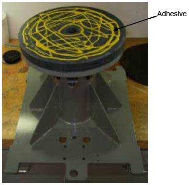 Photograph shows an adhesive that has been applied to the surface of the P V C disk. Arrows indicate the location of the adhesive on the disk.