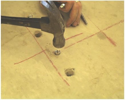Figure 109. Photo. Concrete anchor installation step 6. This photo illustrates the sixth step in concrete anchor installation, where the anchors are tapped into position. A person is lightly hammering in the anchor into the hole that was created in step 3.