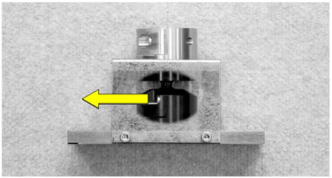 Figure 112. Photo. Proper alignment of ball-joint screws. The photo shows a cutaway view of the assembled ball-joint anchor showing the ball-joint screws facing left towards the opening in the side of the rest stop. An arrow pointing to the left indicates the direction of the screws.