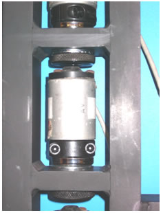 Figure 36. Photo. Attachment of a KUAB geophone in the stand. This photo shows a close-up of an attached KUAB geophone in the stand. The KUAB geophone is bolted to the clamp. The clamp is attached to a magnetic cup, which is bolted into position in the notched shelf of 
the stand.