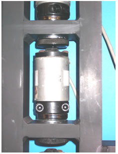 Figure 36. Photo. Attachment of a KUAB geophone in the stand. This photo shows a close-up of an attached KUAB geophone in the stand. The KUAB geophone is bolted to the clamp. The clamp is attached to a magnetic cup, which is bolted into position in the notched shelf of 
the stand.