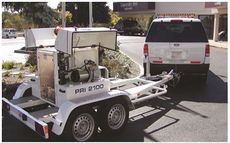 Figure 8. Photo. Carl Bro FWD. This photo shows a Carl Bro model PRI 2100 falling weight deflectometer (FWD) being towed by a Ford<sup>®</sup> sport utility vehicle. The unit is parked in a traffic circle in front of a conference hotel.
