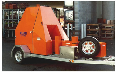 Figure 9. Photo. KUAB FWD with sensors aligned toward the tow vehicle. This photo shows a KUAB falling weight deflectometer (FWD) with an orange cover in the down position. The deflection sensors are aligned toward the tow vehicle, which is not shown. The FWD is in 