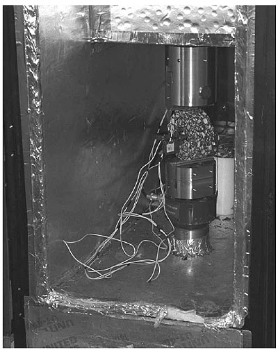 Figure 12 of protocol P07 shows a picture of a typical asphalt specimen mounted in the loading device.  The sample has the gage points and extensometers mounted and ready for testing. The specimen along with the upper and lower arms of the loading device are inside an environmental chamber ready for testing.