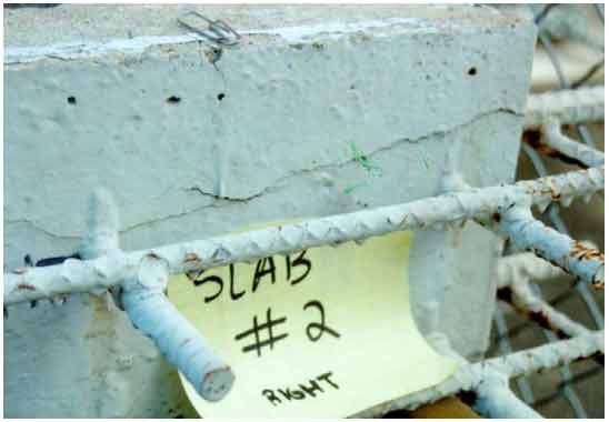 Figure 9. Photo. Crack on the right side of slab 2. This photograph shows cracks on the right side of the slab 2 that primarily originated at the external section of the rebars. On the side of the slab, a horizontal crack either connected or just passed over all four rebars protruding out of the concrete. Rust staining is visible on some of these cracks.