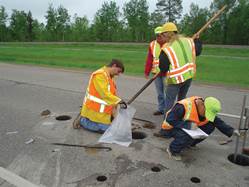 Photo. Workers with safety vests cutting cores in pavement.