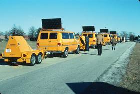 Figure 6.6. Photo. Several van-towed falling weight deflectometers on a roadway.