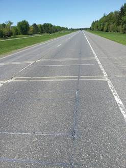 Figure 7.11. Photo. Workers installing a quartz piezoelectric sensor across a full lane.