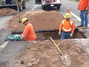 Figure 7.14. Photo. Two workers in safety gear preparing a trench.