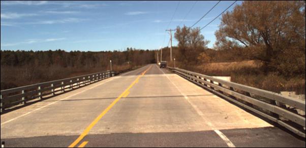 This photo shows the approach to a conventional bridge in the northbound direction. This bridge is a two-way one-lane road and is straight and is located on County Road 31 over Brandy Brook in Lawrence County, NY.