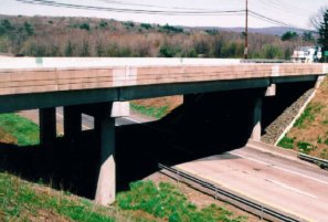 General views of the SR 2042 bridge structures over I-81: A) west bridge and B) east bridge. Photos A and B show that both the west and east bridge spans are supported by two piers, one on either side of the road that the bridge passes over. Each pier has three square concrete columns. 