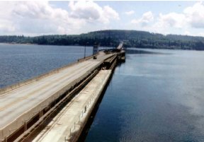 Photo A shows the bridge extending into the water. The elevated bridge has two lanes, and access to the area beneath the bridge deck is provided by a paved lane at the same height as the pontoon deck. In the middle of the canal, the two lanes separate to go around an open area, then rejoin. 