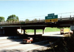 Photo A shows the bridge over Southview Boulevard, which is several lanes each direction. Three columns supporting the middle of the bridge are in the median of the boulevard. 