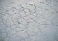 FIGURE 4.  Distress Type ACP 1 - Chicken Wire/Alligator Pattern Cracking Typical in Fatigue Cracking Color photograph of asphalt concrete pavement with distress type ACP 1 - chicken wire/alligator pattern cracking typical in fatigue cracking.  The picture shows an area of  pavement with numerous intersecting cracks that form a pattern of small shapes similar to that of chicken wire or alligator skin.  This pattern is typical in fatigue cracking.